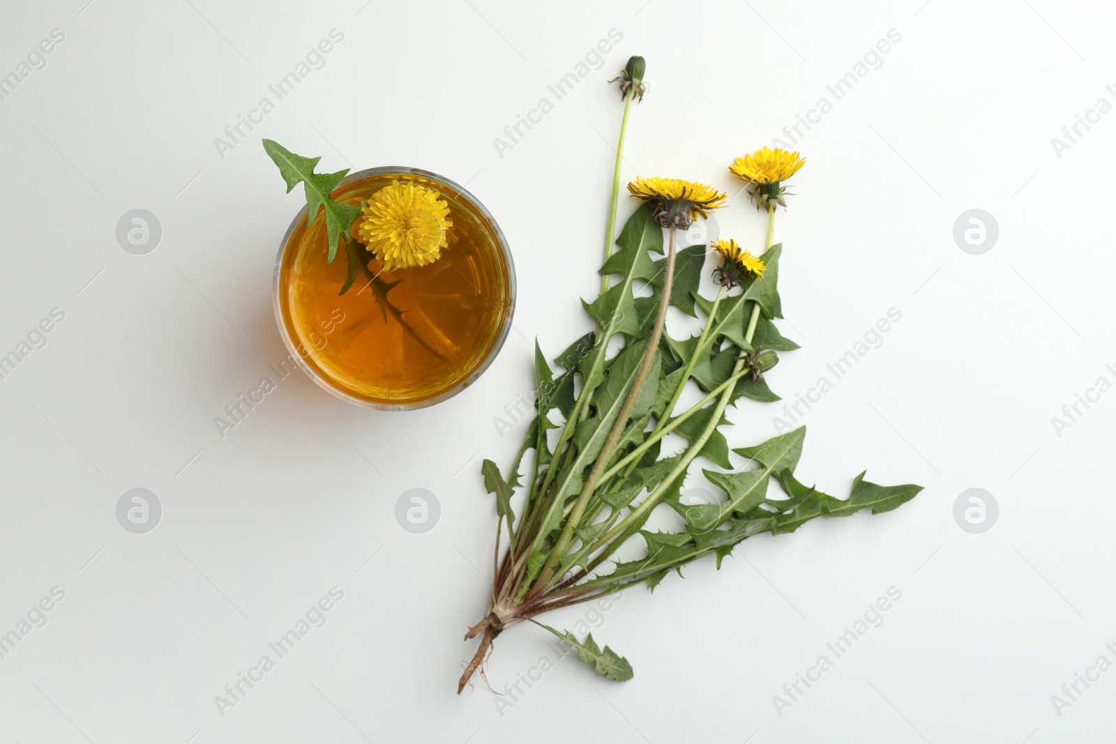 Photo of Delicious fresh tea and beautiful dandelion flowers on white background, top view