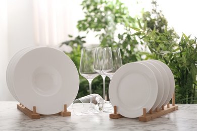 Photo of Set of clean dishware and wineglasses on white table against blurred background