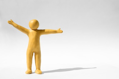 Human figure with arms wide open made of yellow plasticine on white background