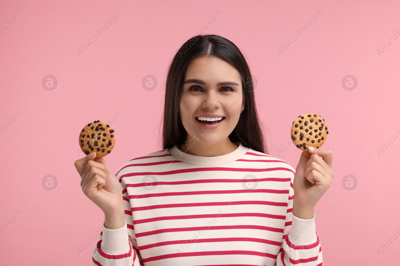 Photo of Young woman with chocolate chip cookies on pink background