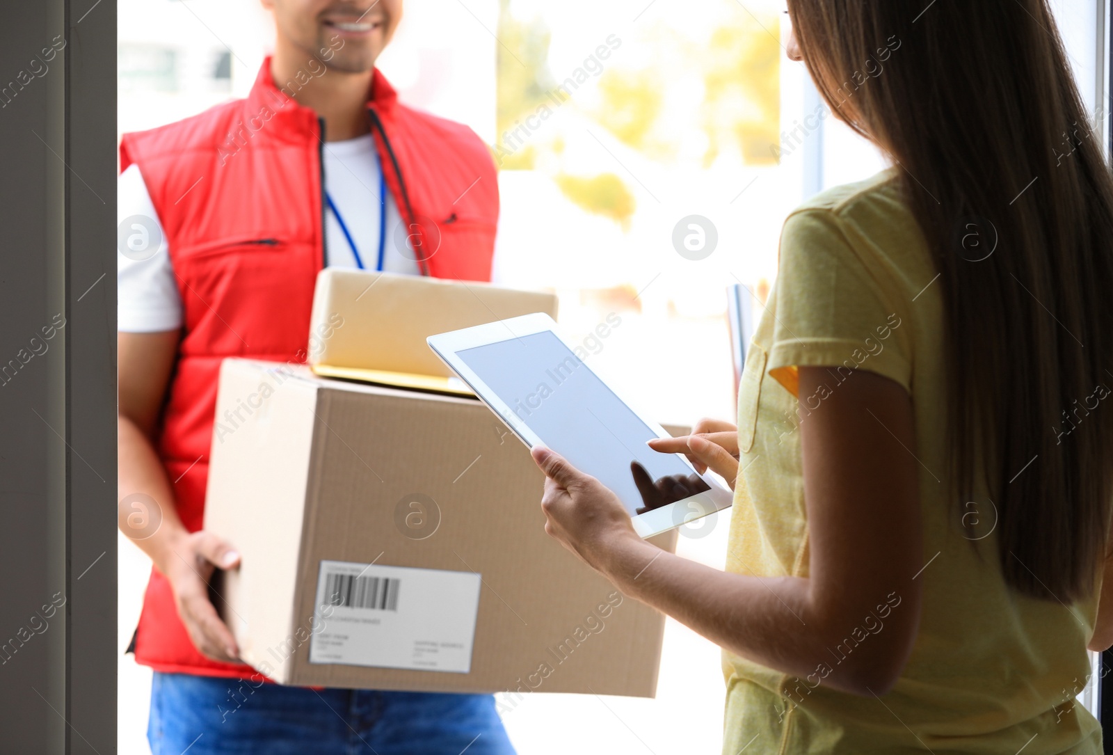 Photo of Woman using app to confirm delivery of parcels from courier on doorstep, closeup