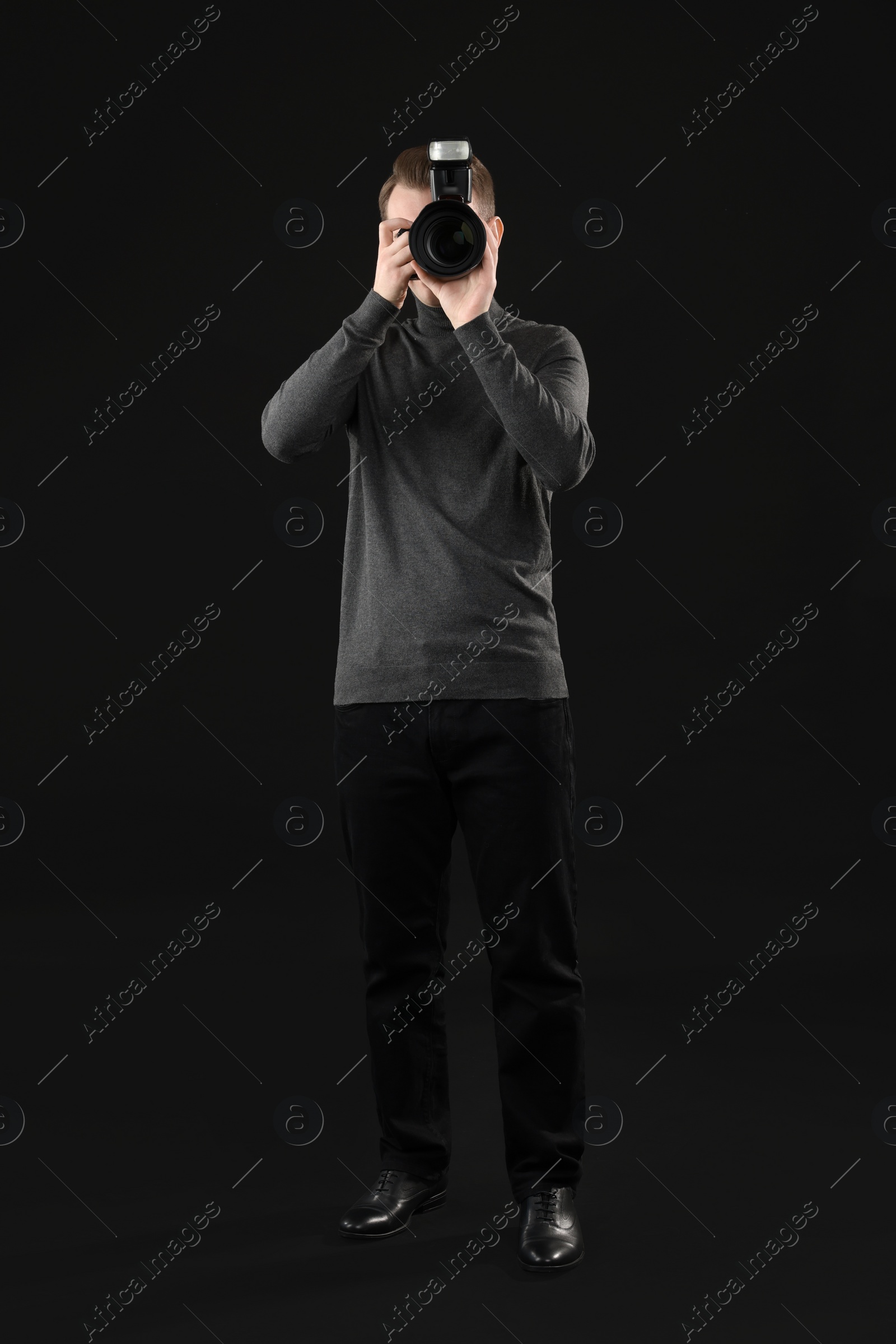 Photo of Professional photographer taking picture on black background