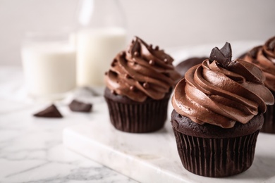 Photo of Delicious cupcakes decorated with cream on white marble table, closeup. Space for text