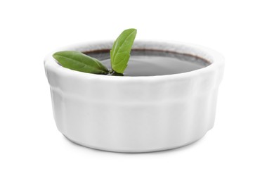 Balsamic glaze with basil leaves in bowl isolated on white