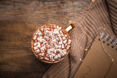 Cup of delicious hot cocoa with marshmallows on wooden table, flat lay