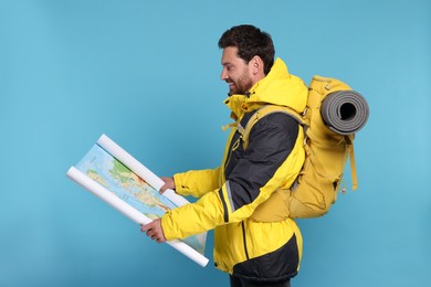 Photo of Happy man with backpack and map on light blue background. Active tourism