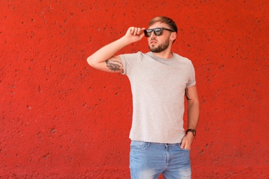 Photo of Young man wearing gray t-shirt near color wall on street