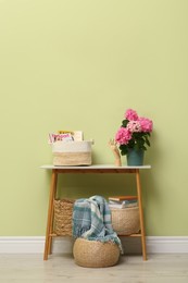 Photo of Console table with beautiful hortensia flower near light green wall in hallway. Interior design