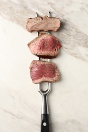 Photo of Delicious sliced beef tenderloin with different degrees of doneness on marble board, top view