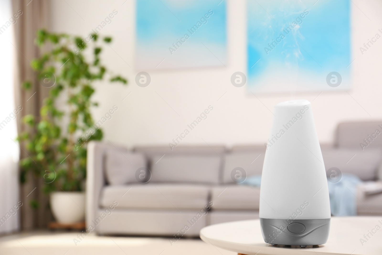 Photo of Modern essential oil diffuser on table in room. Space for text