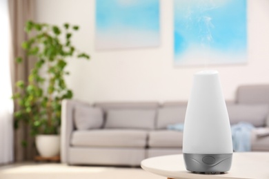 Modern essential oil diffuser on table in room. Space for text