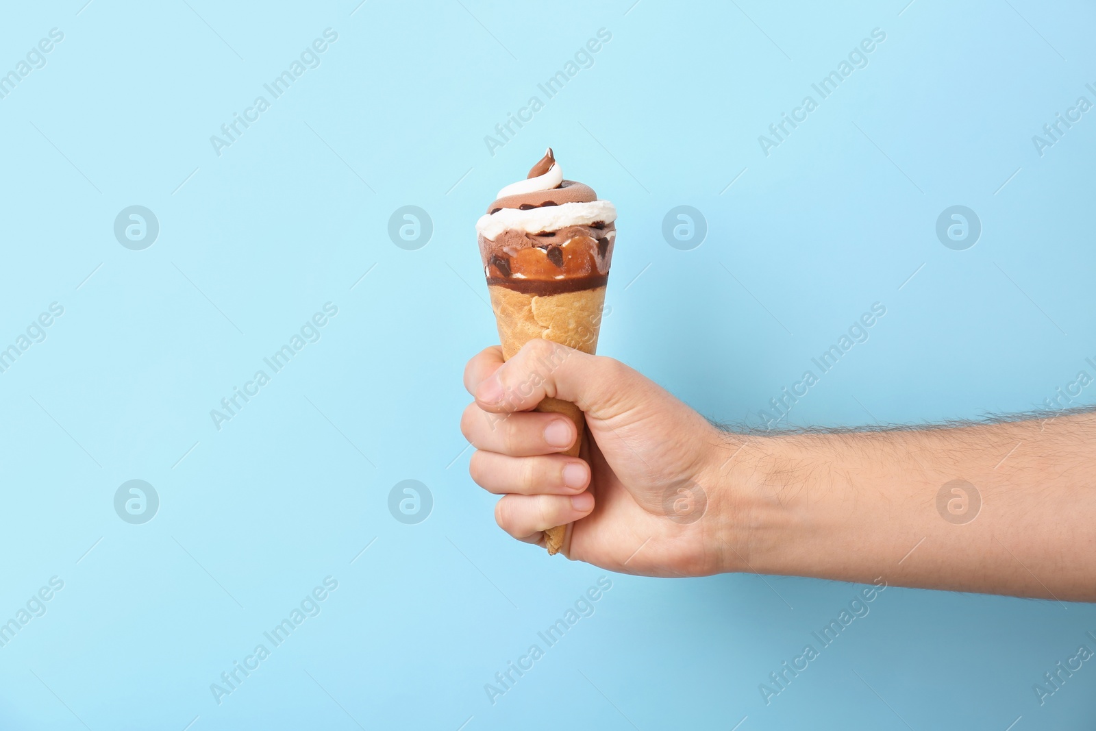 Photo of Man holding yummy ice cream on color background. Focus on hand