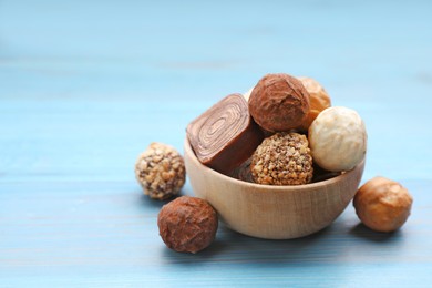 Tasty chocolate candies on light blue wooden table. Space for text