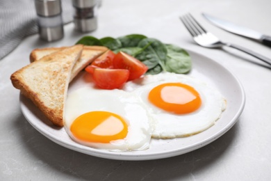 Photo of Tasty breakfast with fried eggs, toasts and spinach served on light grey table, closeup