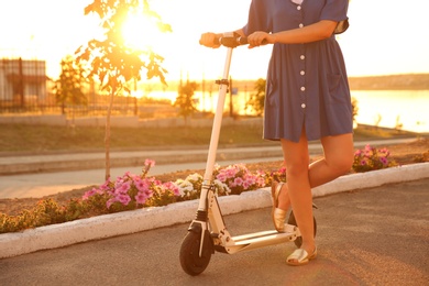 Photo of Woman with electric kick scooter outdoors on sunny day, closeup
