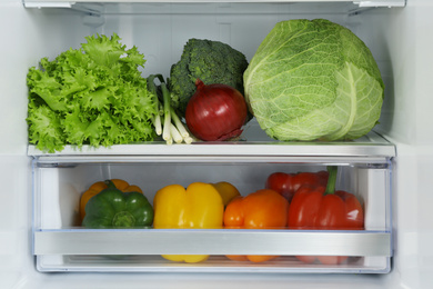 Photo of Open refrigerator full of fresh vegetables, closeup