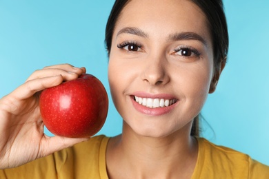 Photo of Young woman with healthy teeth and apple on color background, closeup
