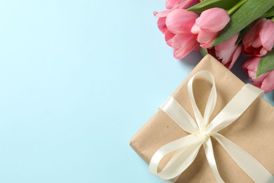 Photo of Happy Mother's Day. Beautiful pink tulips and gift box on light blue background, flat lay. Space for text