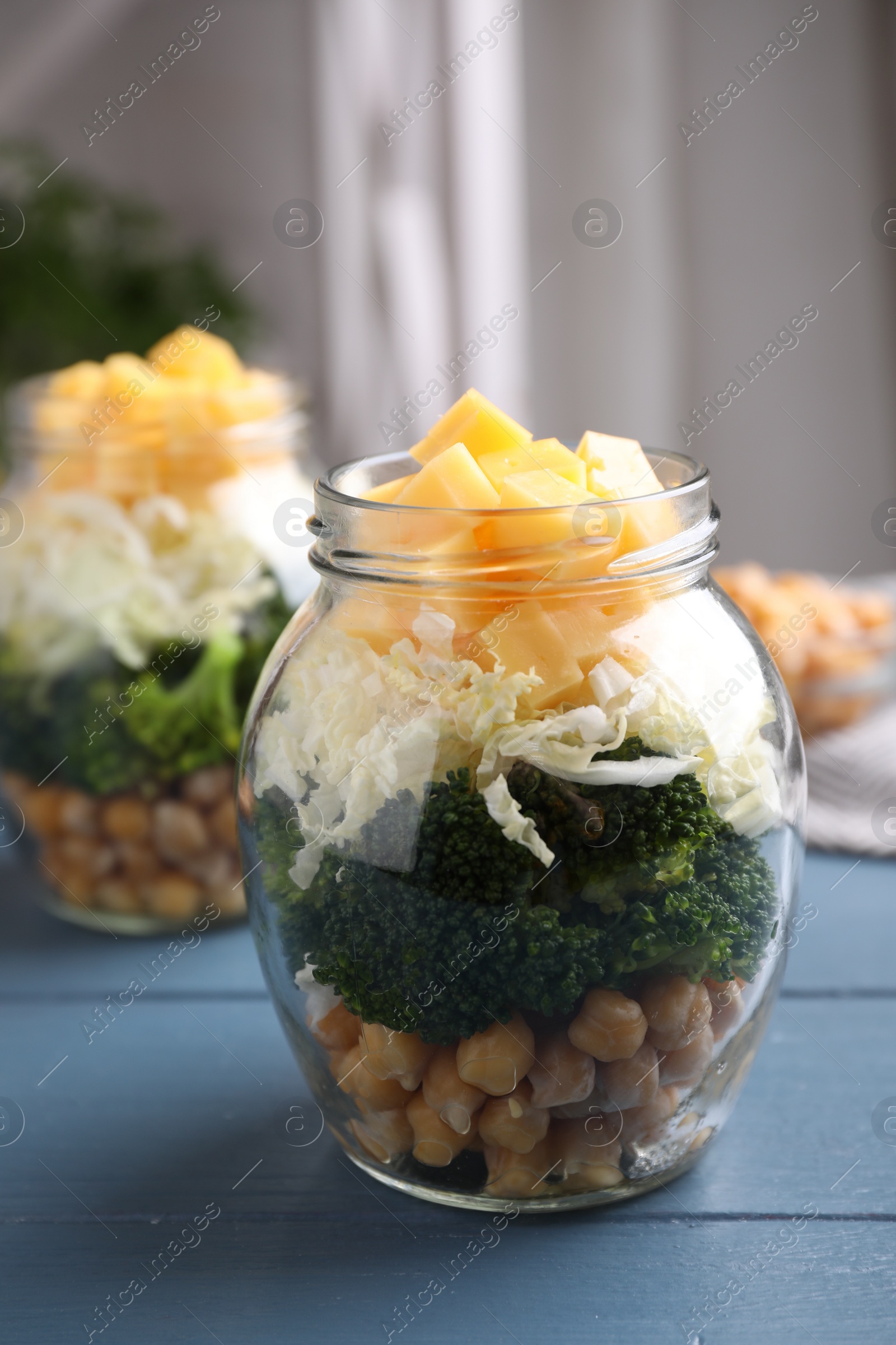 Photo of Healthy salad in glass jar on blue wooden table