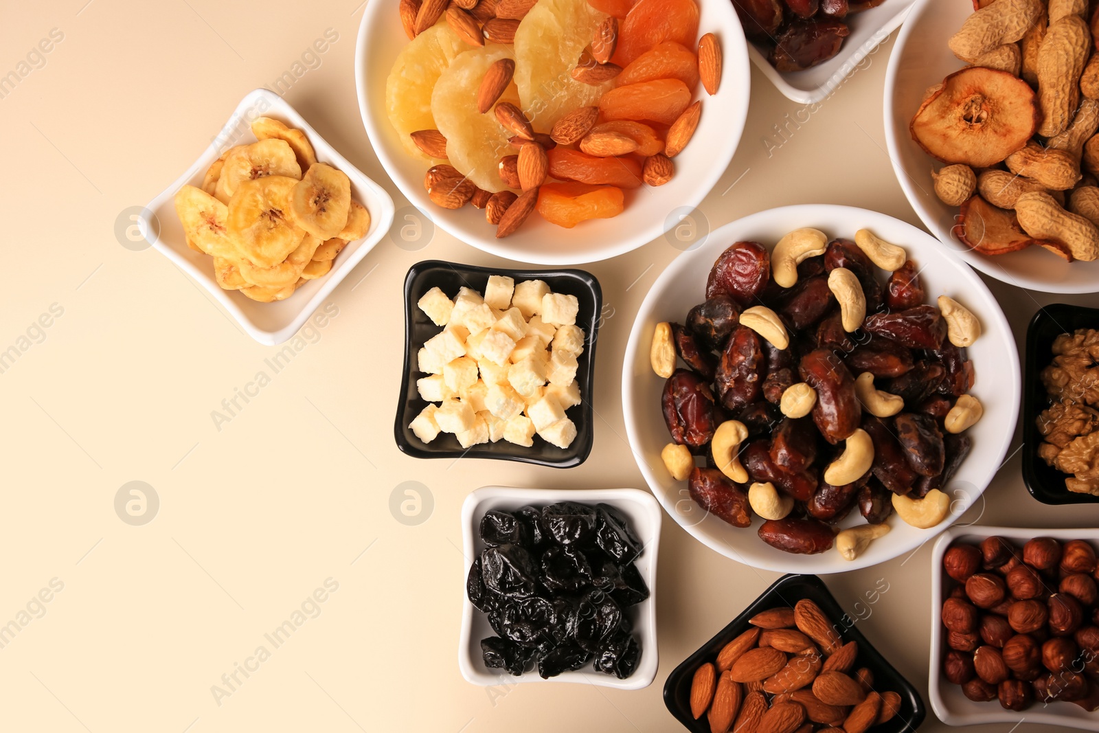 Photo of Bowls with dried fruits and nuts on beige background, flat lay. Space for text