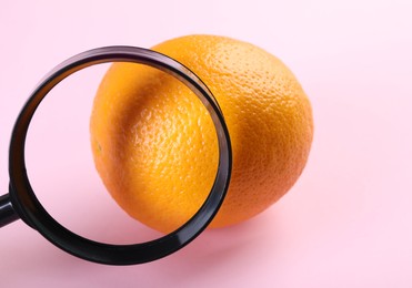 Photo of Cellulite problem. Orange and magnifying glass on pink background