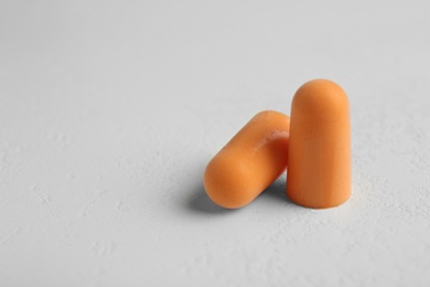 Photo of Pair of orange ear plugs on grey background, closeup. Space for text