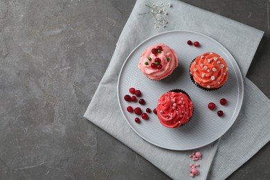 Photo of Delicious cupcakes with pink cream and berries on grey table, top view. Space for text