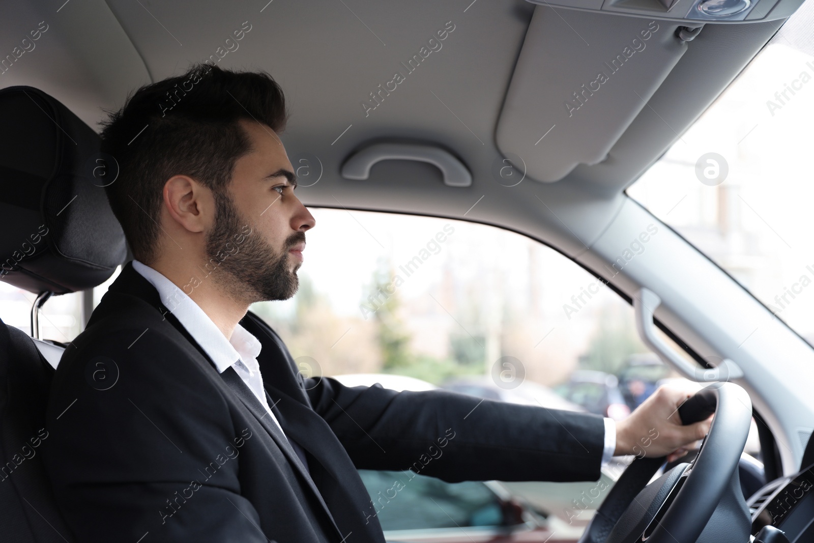 Photo of Handsome young man driving his modern car
