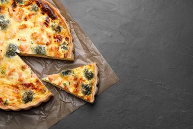 Delicious homemade quiche with salmon and broccoli on black table, top view. Space for text