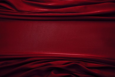 Delicate dark red silk fabric as background, top view. Space for text