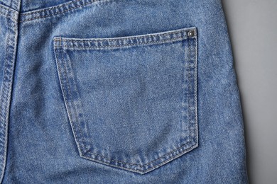 Jeans with pocket on grey background, top view