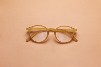 Photo of Glasses with corrective lenses on light brown background, top view