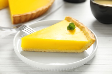 Slice of delicious homemade lemon pie on white wooden table