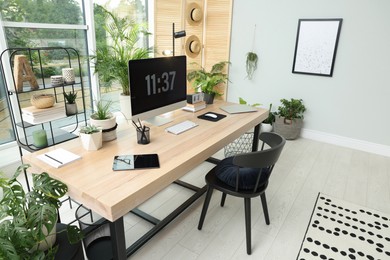Photo of Comfortable workplace with computer in light room. Interior design