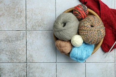 Photo of Soft woolen yarns, knitting and needles on grey tiled background, flat lay. Space for text