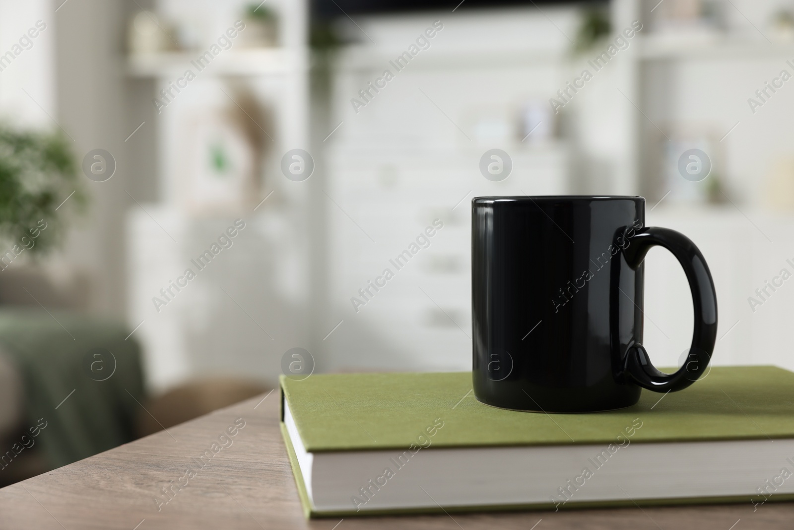 Photo of Blank ceramic mug and book on wooden table. Mockup for design