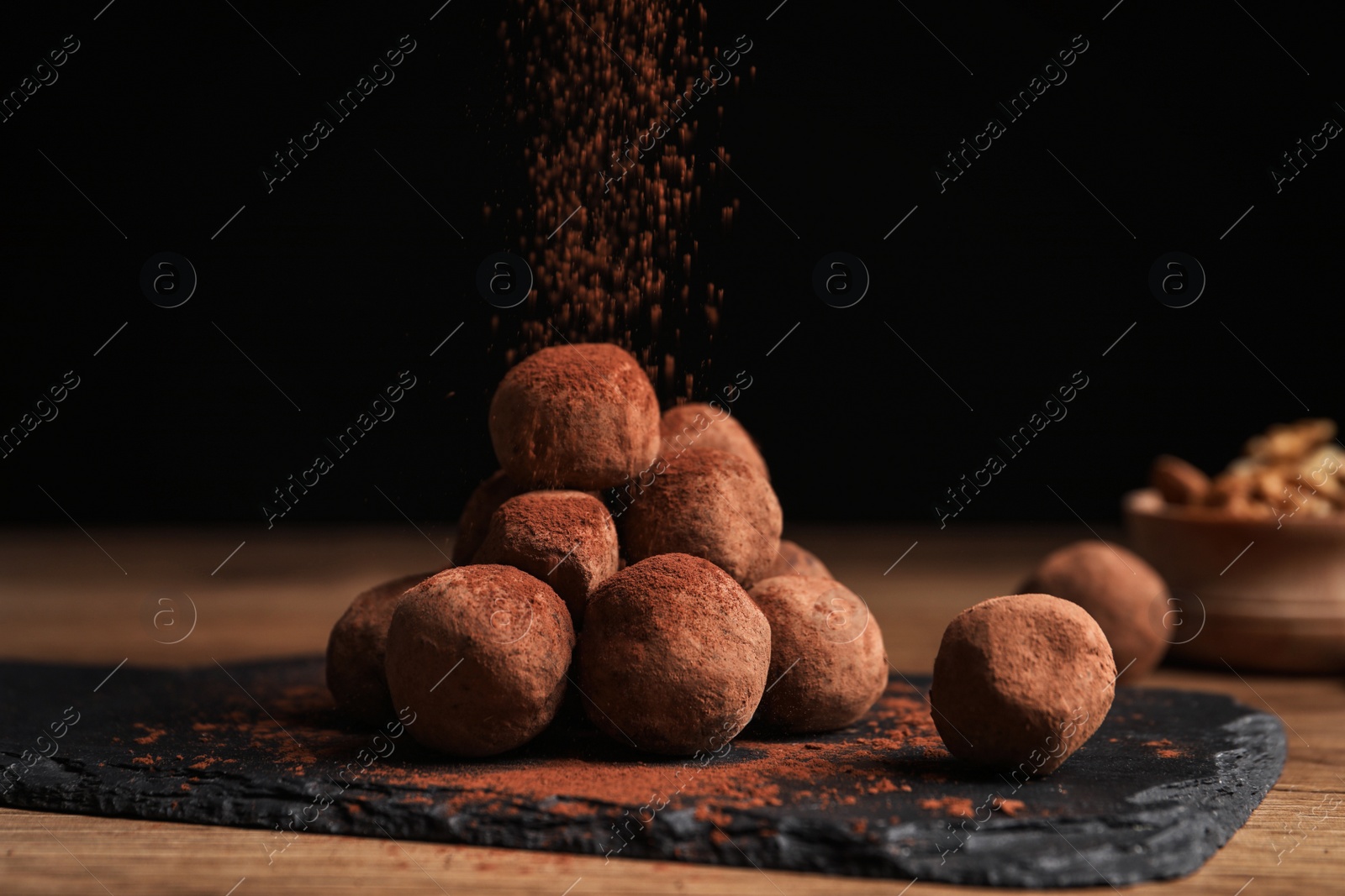 Photo of Tasty chocolate truffles powdered with cacao on slate board