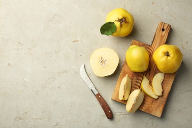 Photo of Tasty ripe quince fruits and knife on grey table, flat lay. Space for text