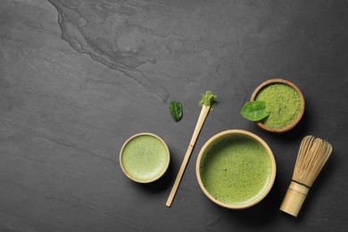 Photo of Fresh matcha tea, bamboo whisk, spoon and green powder on black table, flat lay. Space for text