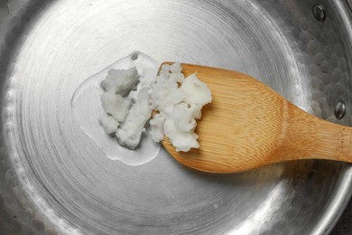 Frying pan with coconut oil and wooden spatula, top view. Healthy cooking