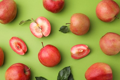 Photo of Tasty apples with red pulp and leaves on light green background, flat lay