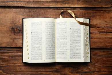 Photo of Open Bible on wooden table, top view. Christian religious book