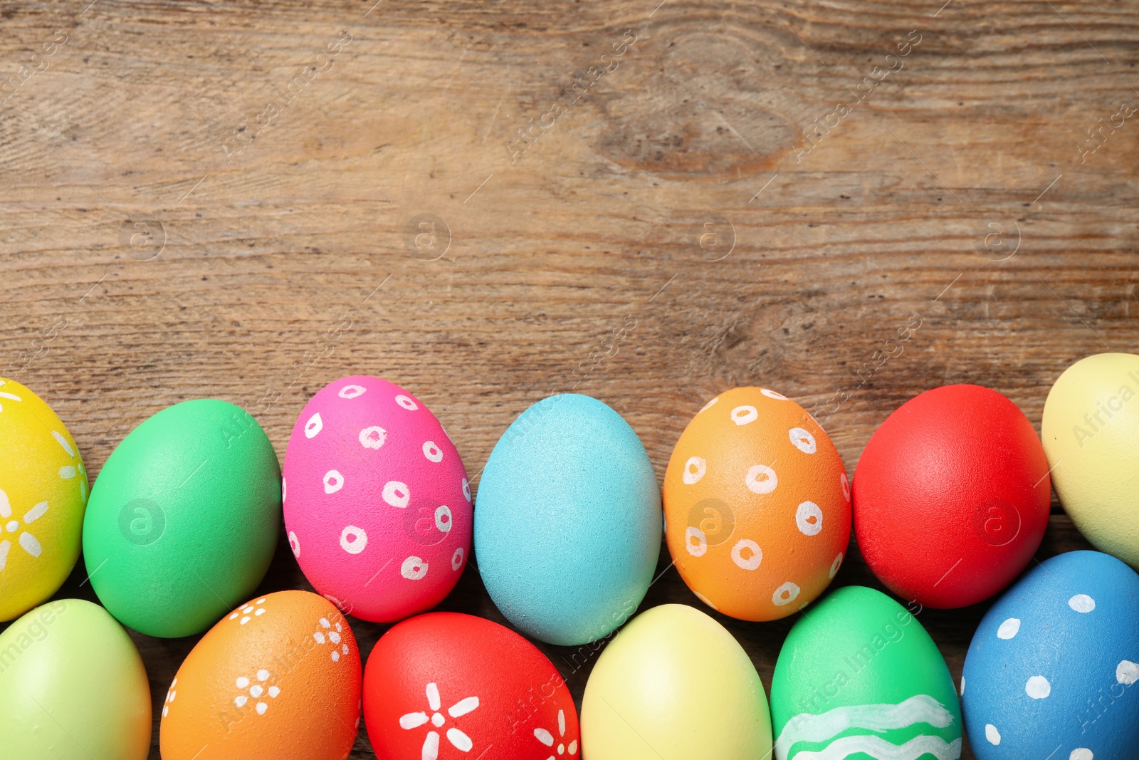 Photo of Colorful Easter eggs on wooden background, flat lay. Space for text