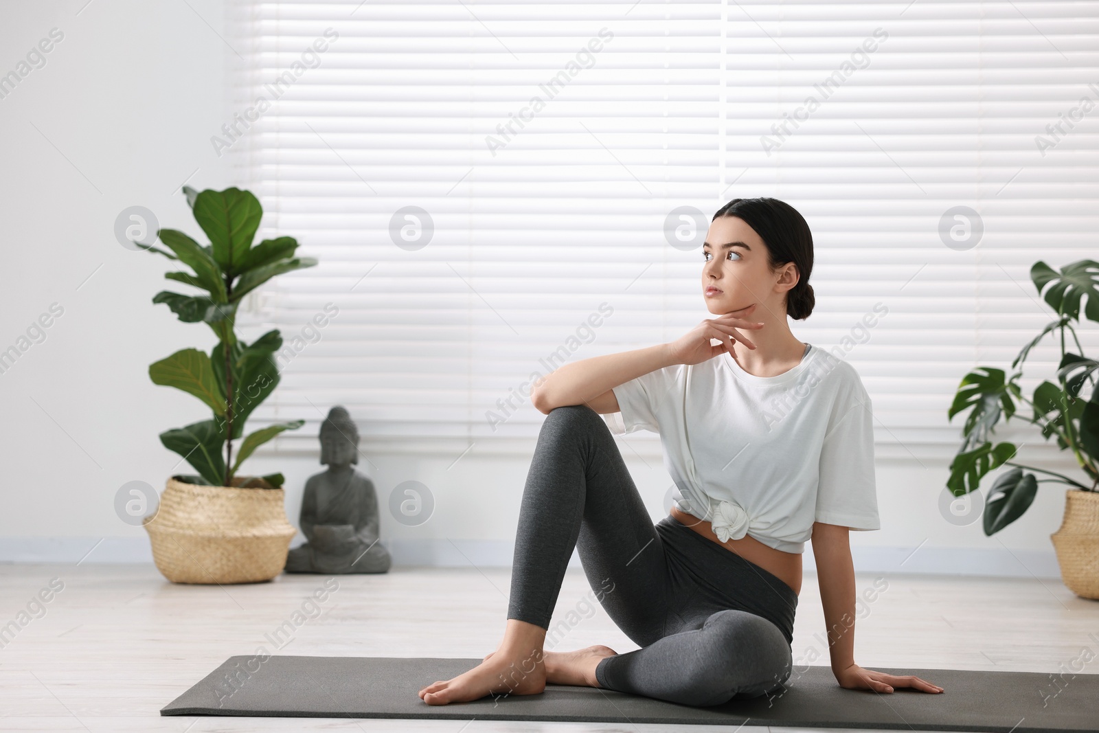 Photo of Beautiful girl sitting on yoga mat in studio