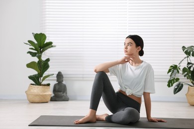 Beautiful girl sitting on yoga mat in studio