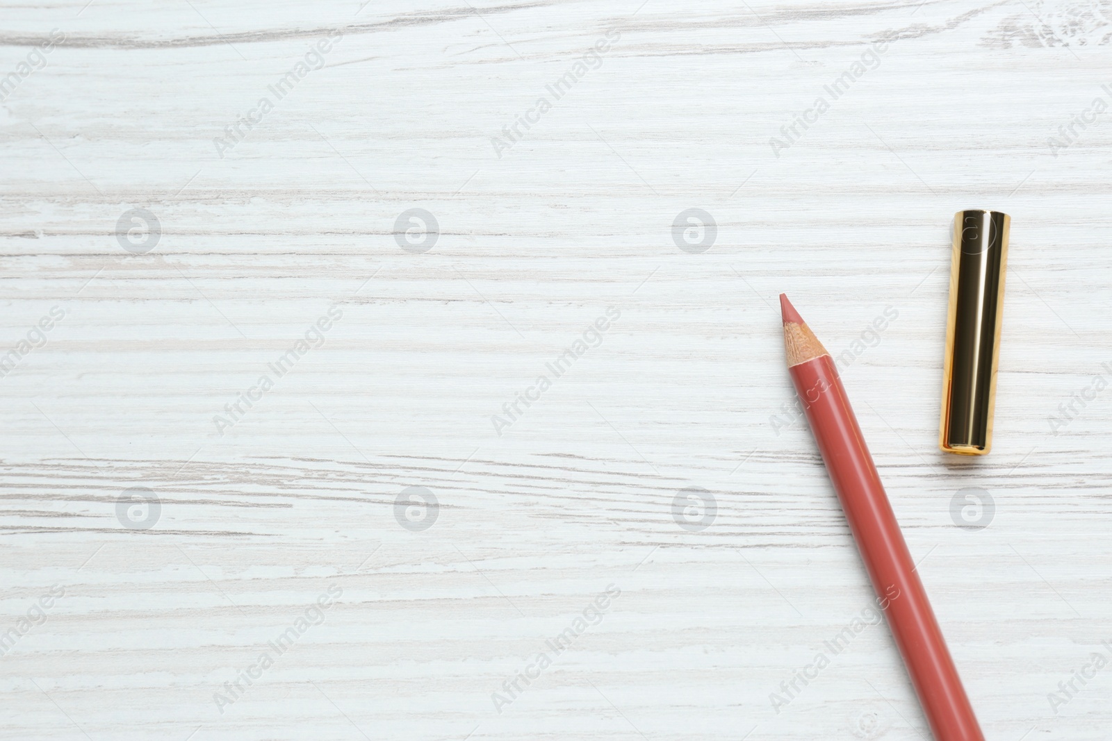 Photo of Lip pencil on white wooden table, flat lay. Space for text