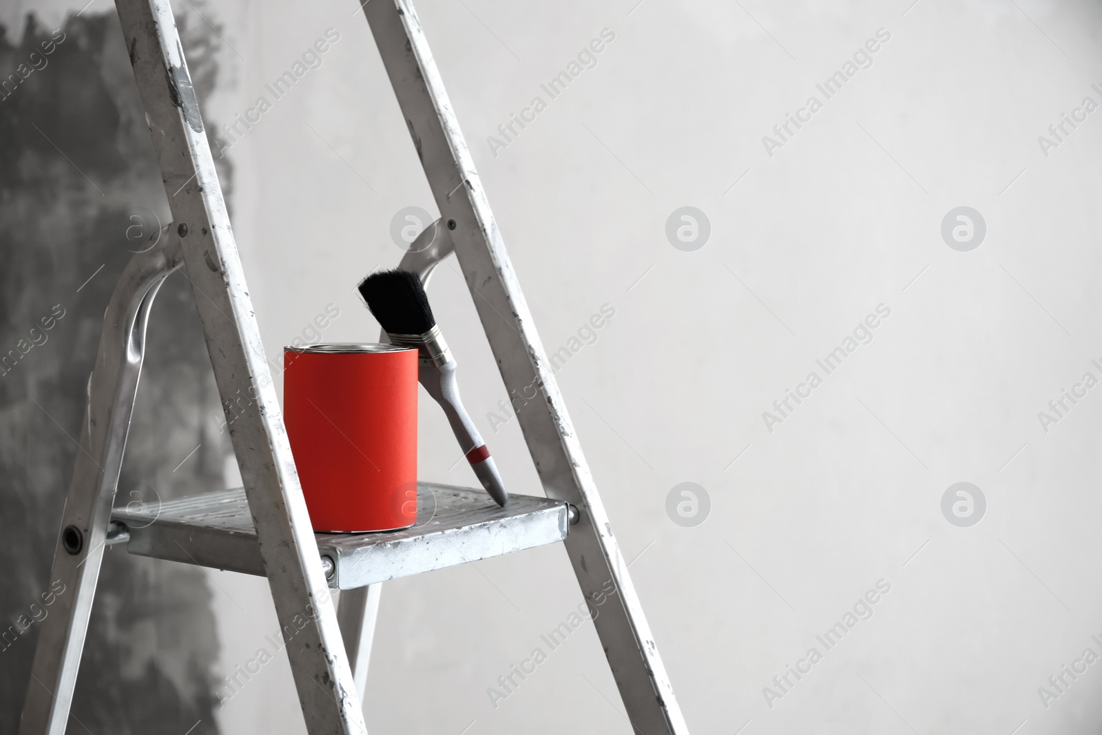 Photo of Can with paint and brush on step ladder in room