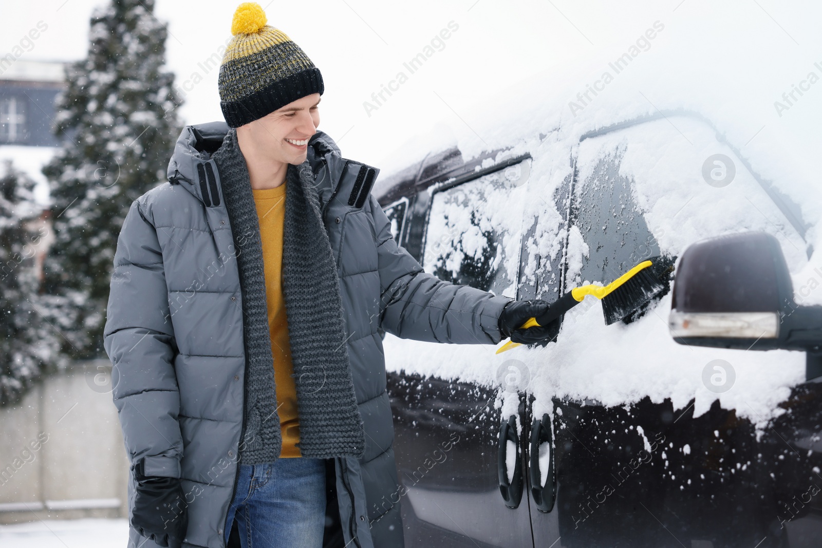 Photo of Man cleaning snow from car window outdoors