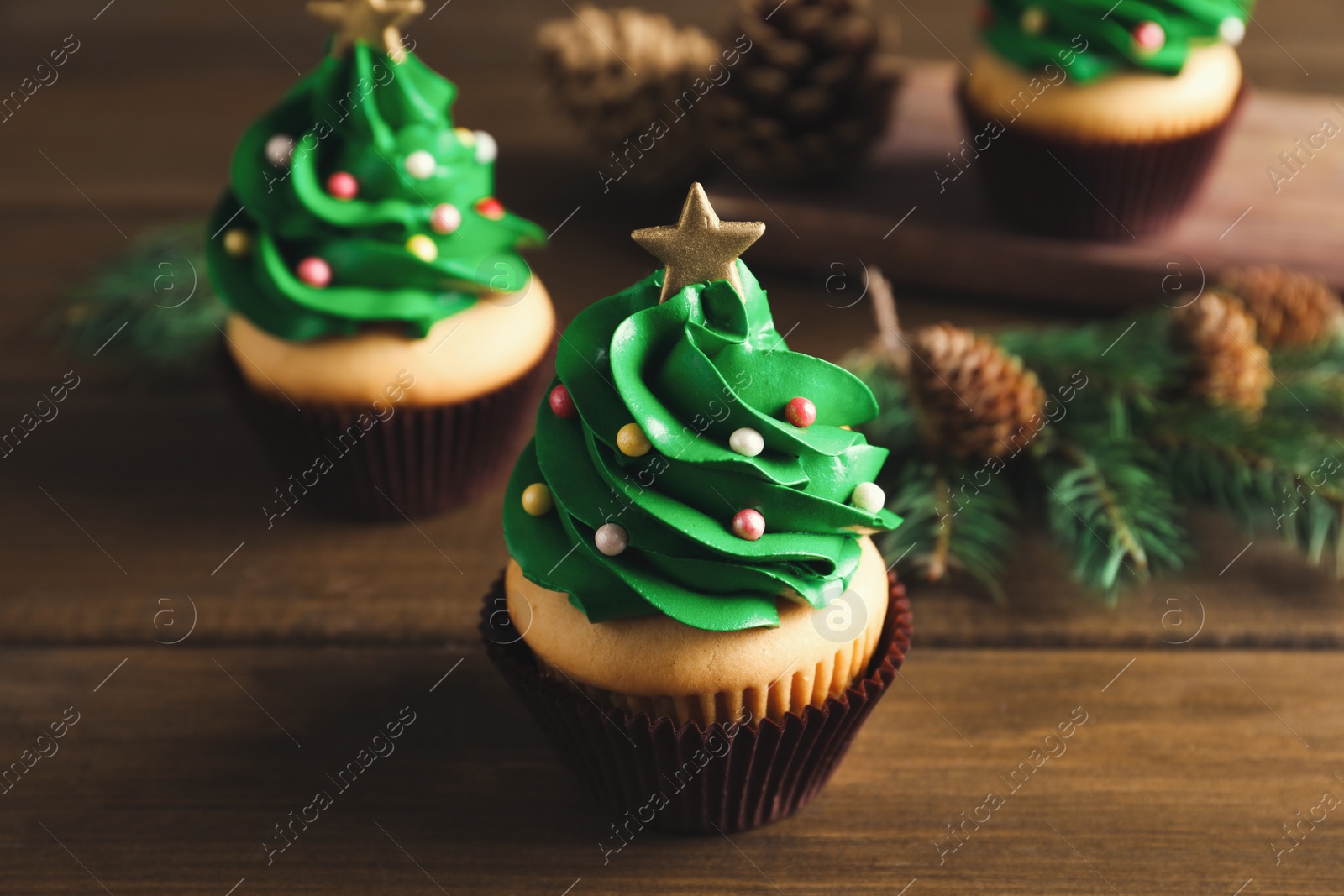 Photo of Christmas tree shaped cupcakes on wooden table
