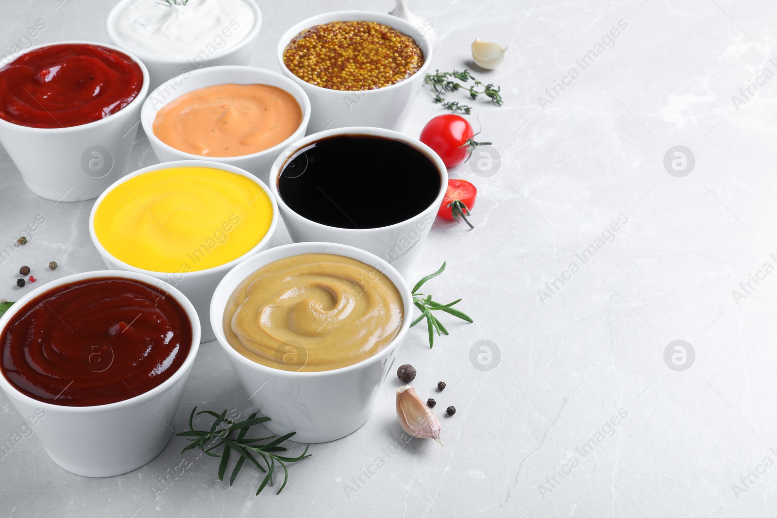 Photo of Many bowls with different sauces on light grey table, space for text